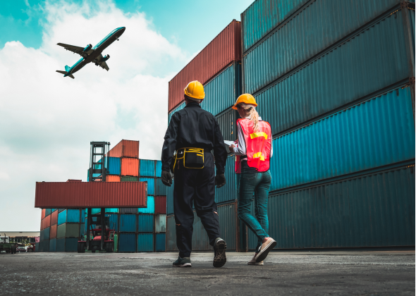 Technicians work around a cargo bay, a plane flies overhead